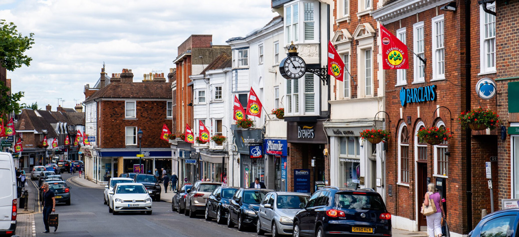 Scenic view of Sevenoaks town centre with historic buildings, red flags, and street-side parking.