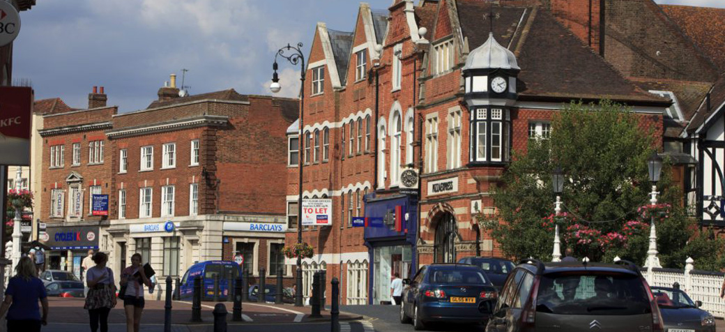 Busy high street in Tonbridge showing local shops, Barclays bank, and parked cars.