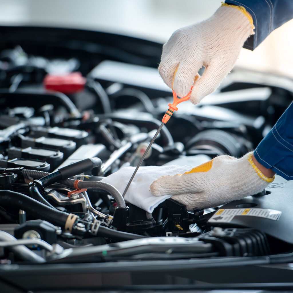 Close-up of hands checking vehicle dipstick for engine maintenance and safety