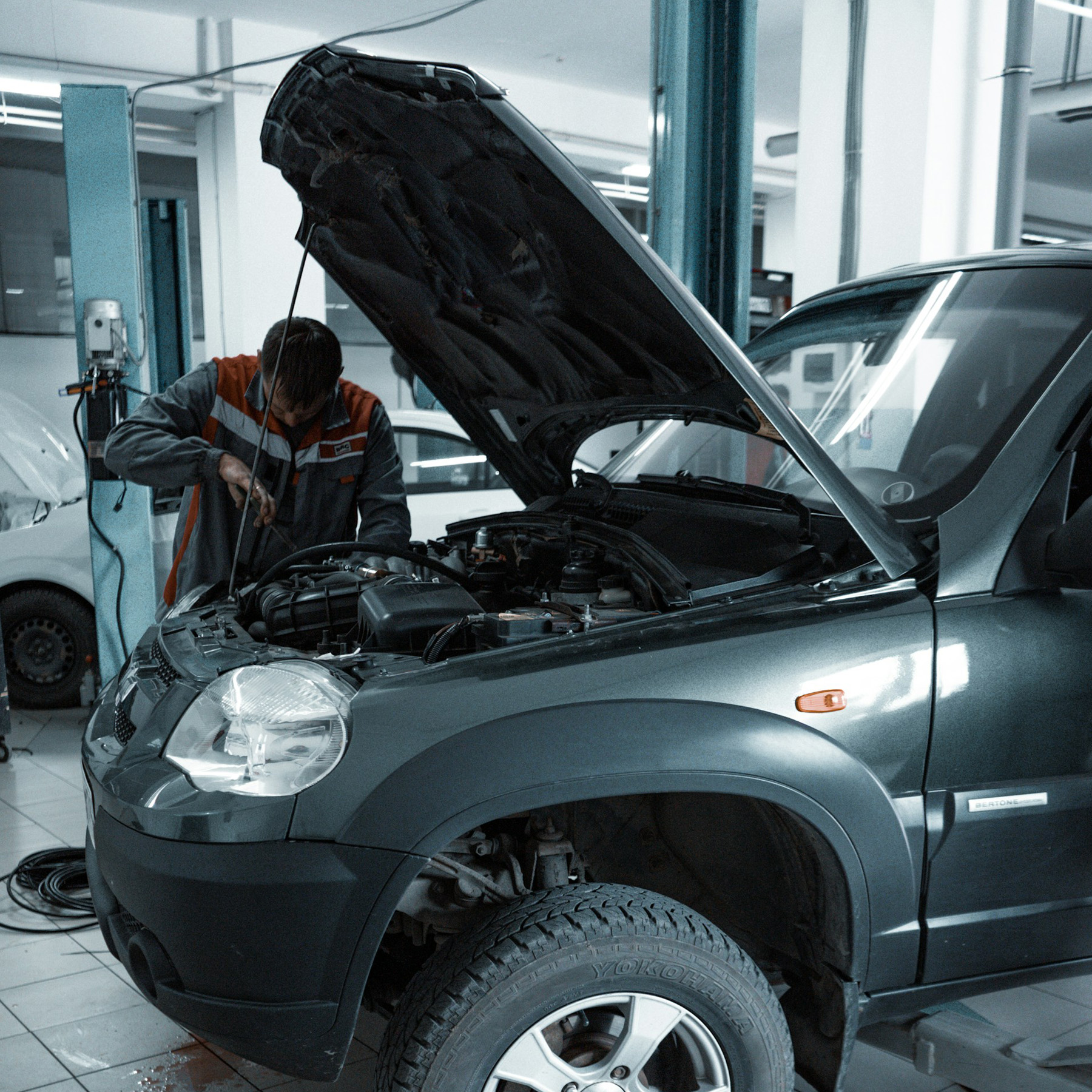 Car mechanic inspecting a vehicle engine with the hood open for professional diagnostic troubleshooting.