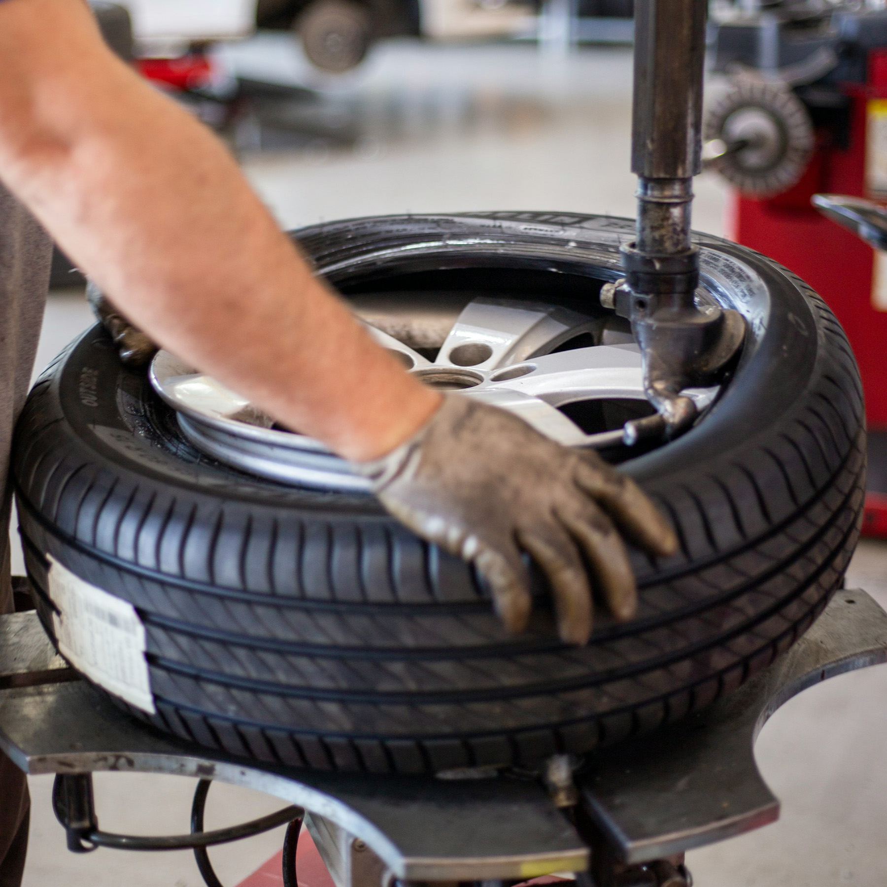 Technician fitting a new tyre on a wheel rim for local tyre and exhaust services.