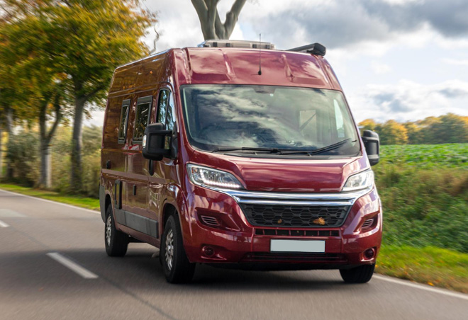 Red commercial service van driving on a road, representing fleet maintenance services for local businesses.